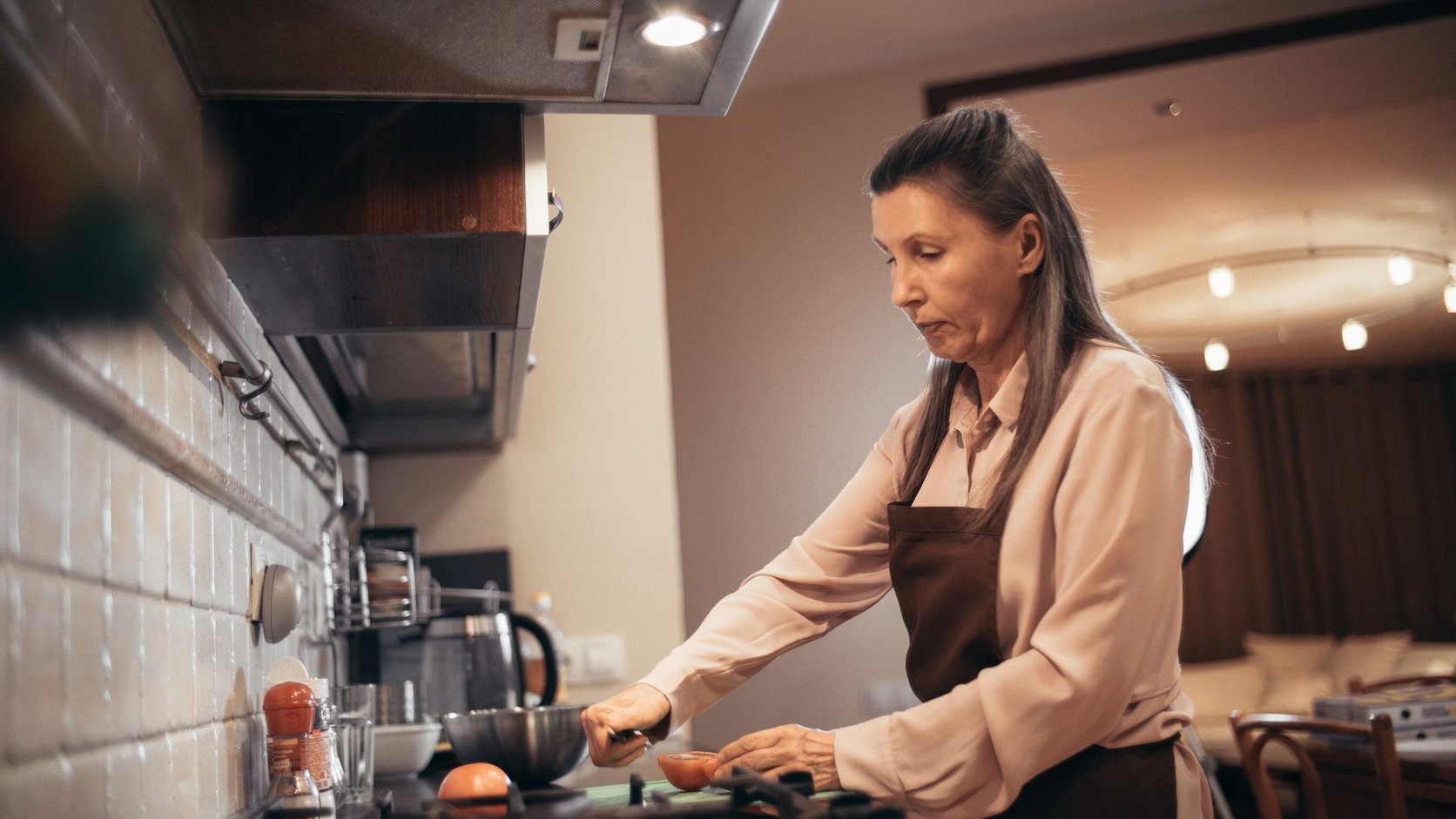 Mulher madura preparando uma refeição saudável na cozinha de casa com luz natural