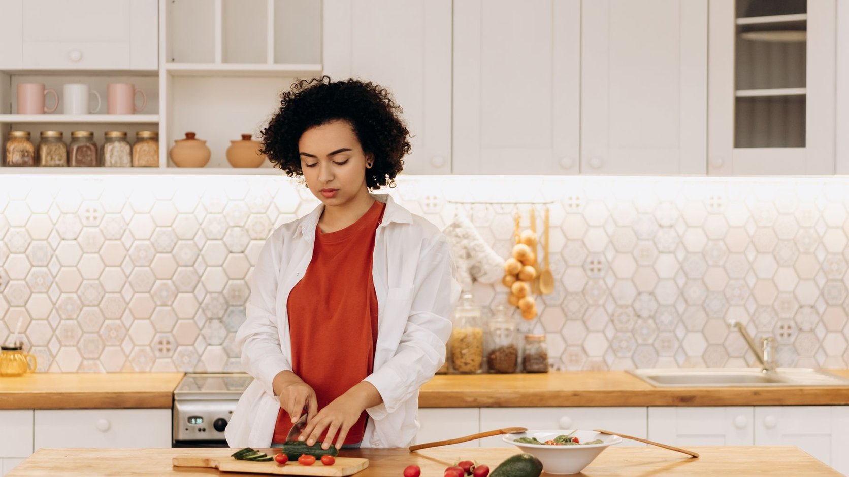 Mulher preparando legumes em cozinha de casa para uma refeição simples e equilibrada