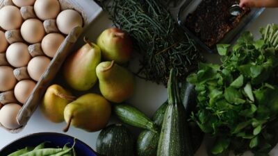 Bandeja com ovos, peras, verduras, legumes e pao em visao superior — representacao de alimentacao real e equilibrada