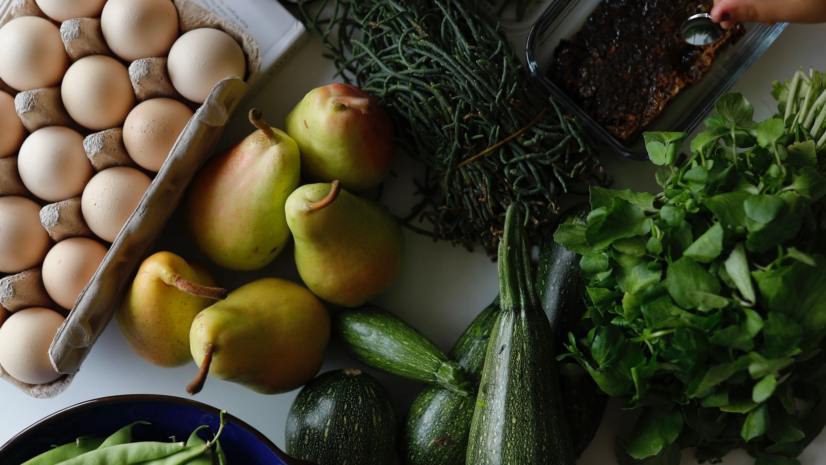 Bandeja com ovos, peras, verduras, legumes e pao em visao superior — representacao de alimentacao real e equilibrada