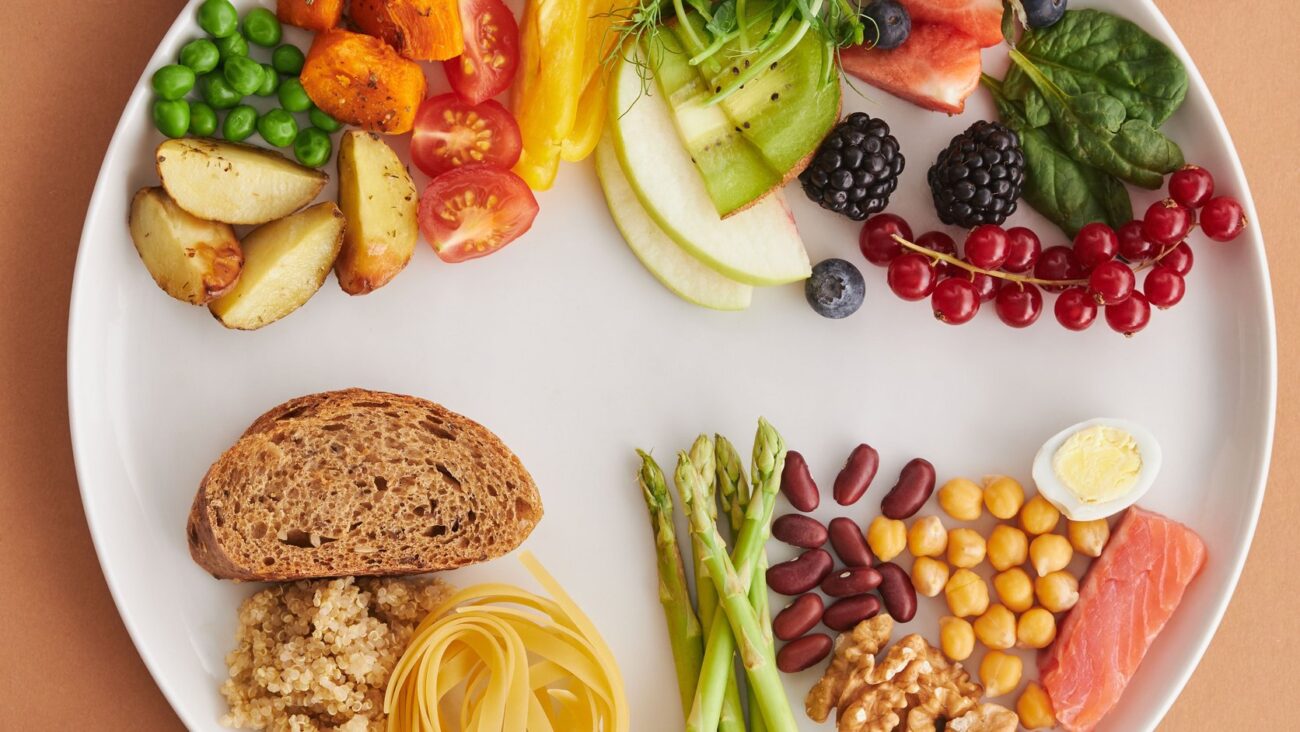 Variedade colorida de alimentos anti-inflamatorios como frutas vermelhas vegetais nozes e sementes dispostos em prato sobre mesa de madeira