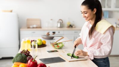 Mulher preparando salada saudável na cozinha, alimentação equilibrada no dia a dia
