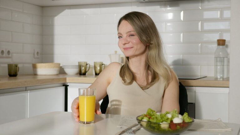 Mulher sorridente saboreando salada fresca em cozinha moderna