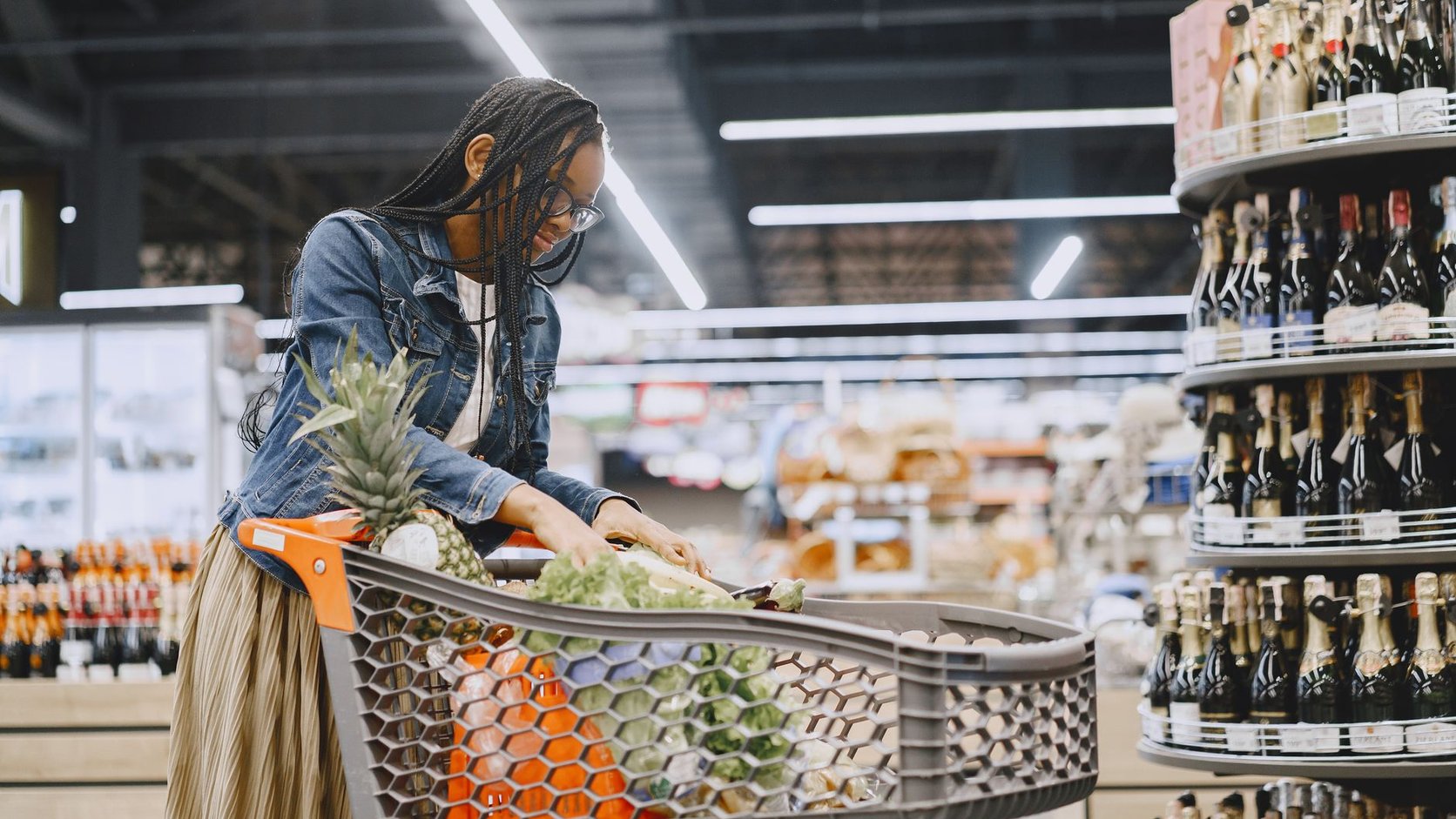 Mulher com carrinho de compras cheio de frutas e legumes frescos