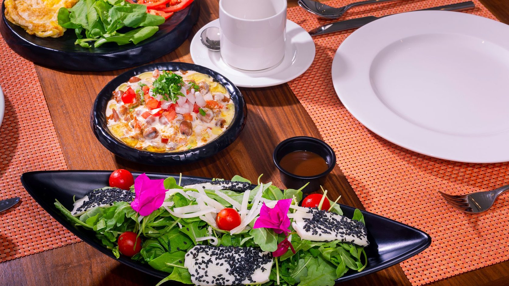 Mesa de café da manhã colorida com salada, omelete e pratos laterais