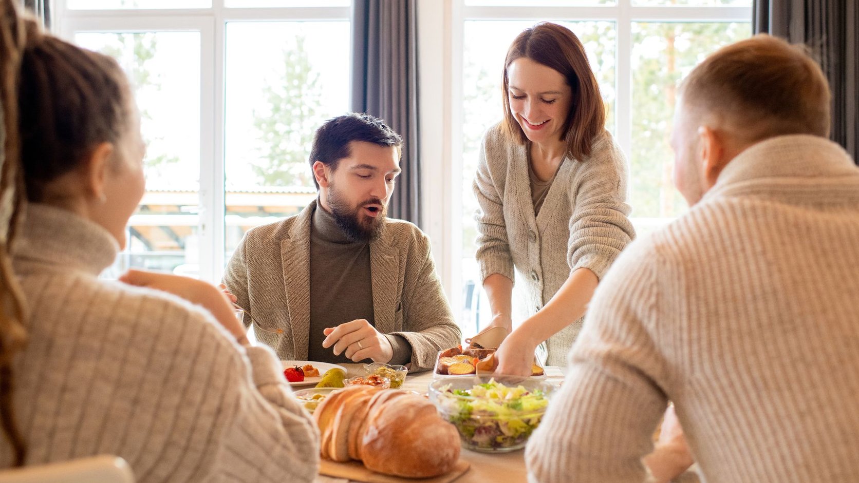 Grupo de amigos rindo ao redor de mesa com refeições variadas