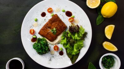 Peixe grelhado servido com salada fresca e espinafre em prato branco