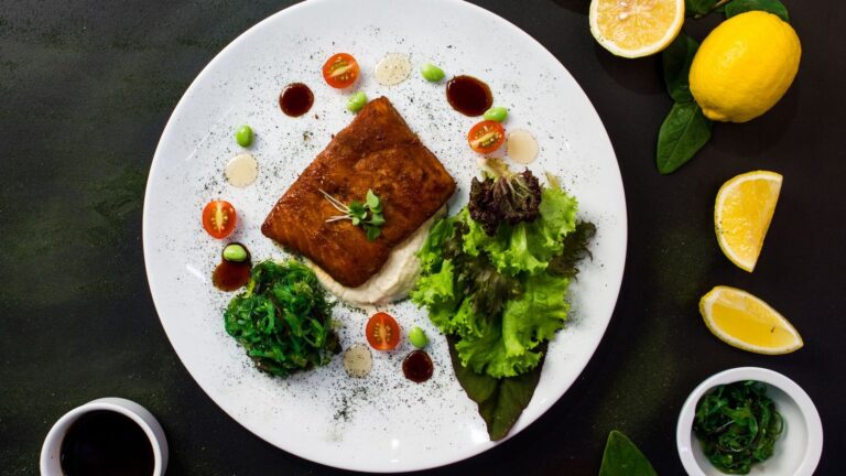 Peixe grelhado servido com salada fresca e espinafre em prato branco