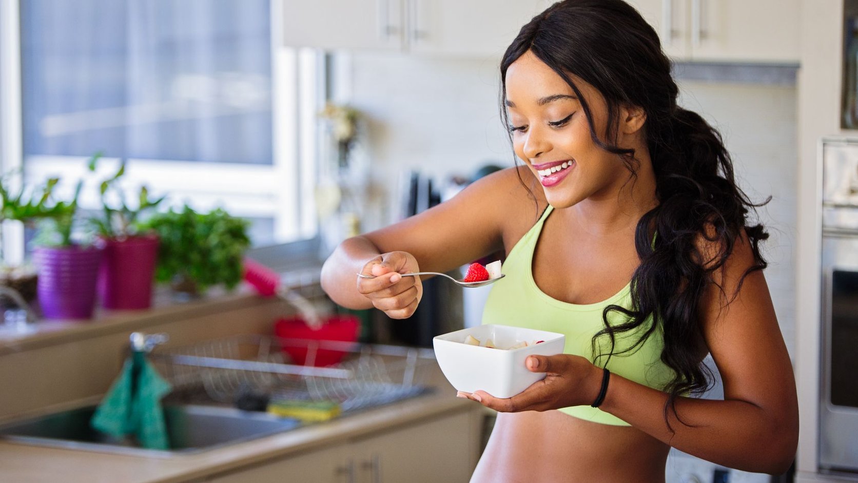 Mulher sorridente em sua cozinha preparando alimentos frescos e saudáveis.