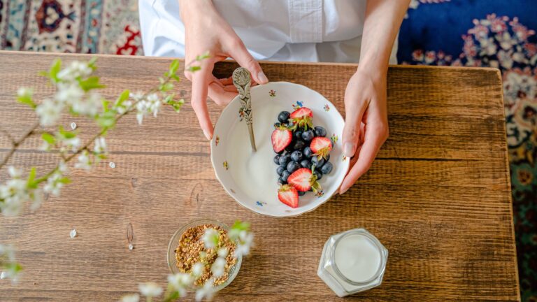 Preparo de tigela matinal com frutas frescas, iogurte natural e grãos sem açúcar adicionado.