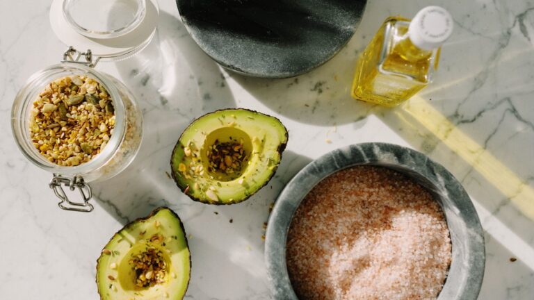 Metades de abacate fresco salpicadas com sementes nutritivas em iluminação natural.
